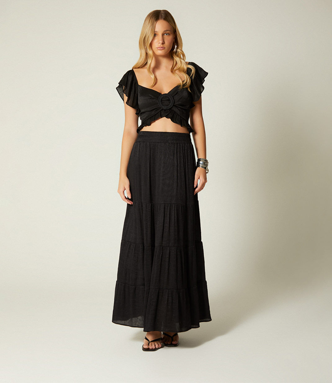 Dos mujeres luciendo look en negro compuesto por conjunto de falda y crop top, vestido largo y gafas de sol